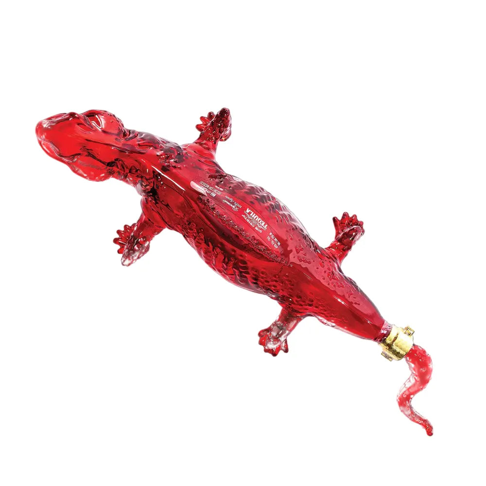 Decorative glass tequila decanter shaped like a vibrant translucent red lizard featuring textured scales, a distinctive gold band near its curly tail, and "TEQUILA" embossed on its side