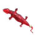 Decorative glass tequila decanter shaped like a vibrant translucent red lizard featuring textured scales, a distinctive gold band near its curly tail, and "TEQUILA" embossed on its side