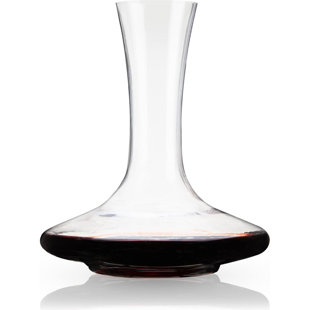 Clear glass wine decanter with a slender neck and wide flared base filled with deep red wine on a reflective white surface