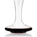 Clear glass wine decanter with a slender neck and wide flared base filled with deep red wine on a reflective white surface