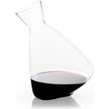 Clear glass wine decanter with an elegant tilted design holding dark red wine on a reflective white background