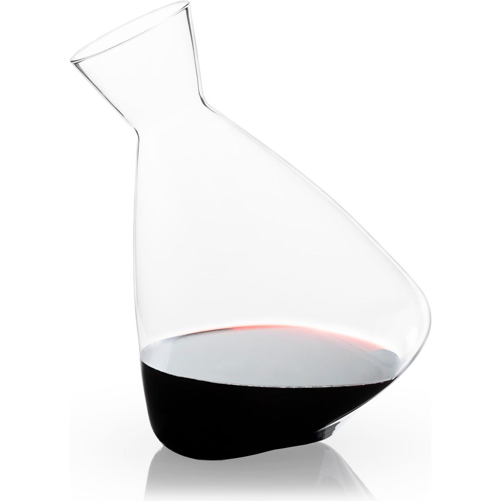 Clear glass wine decanter with an elegant tilted design holding dark red wine on a reflective white background