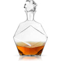Clear geometric faceted glass decanter with a matching faceted crystal stopper containing warm amber liquid